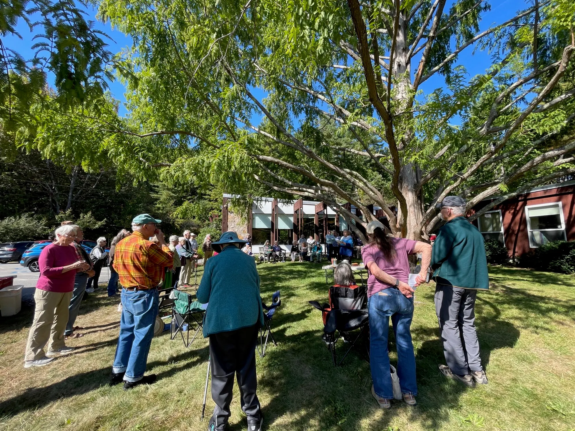 The congregation gathered in a circle on the lawn under the dawn redwood, the church building behind them
